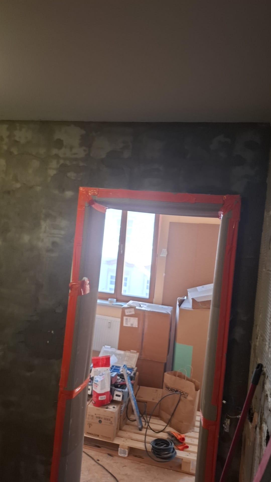 Zamaskované zárubně a nová omítka stěny během realizace